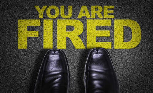 A pair of black shoes standing on a surface with the words 'YOU ARE FIRED' in yellow