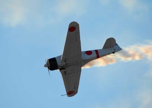 A vintage military airplane performing an aerial maneuver against a blue sky