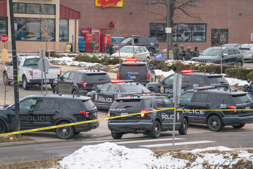 Multiple police vehicles at a scene with caution tape and emergency lights activated