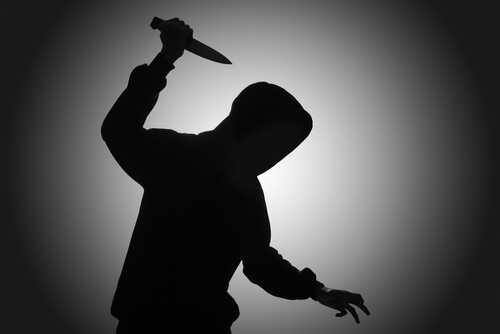 Silhouette of a person holding a knife in a threatening manner