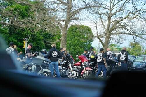 Group of bikers gathered around their motorcycles in an outdoor setting