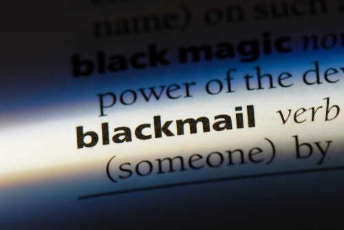 Close-up of a dictionary page showing the definition of 'blackmail'