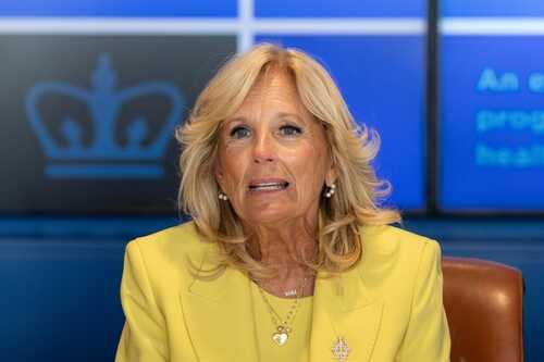A woman in a yellow blazer speaking at a conference