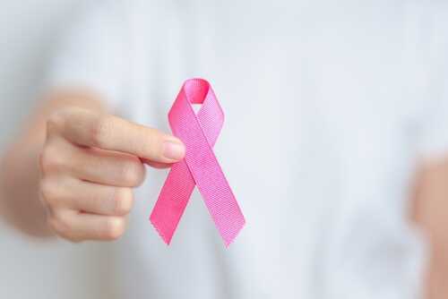 Person holding a pink ribbon symbolizing awareness
