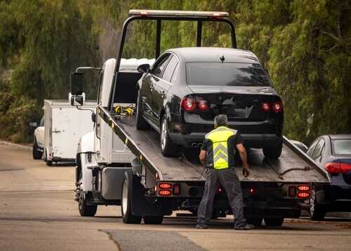 A tow truck lifting a black car onto its flatbed