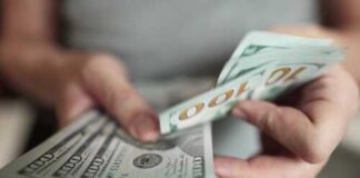 Person counting stacks of hundred dollar bills