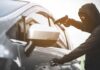 A masked individual attempting to steal a car with a gun