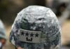 Close-up of a military helmet featuring a camouflage pattern and five-star insignia