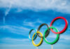 Olympic rings against a bright blue sky backdrop