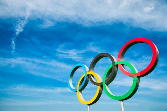 Olympic rings against a bright blue sky backdrop