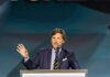 Tucker Carlson Ignites MAGA Israel Uproar Man speaking at podium with microphone and gesturing