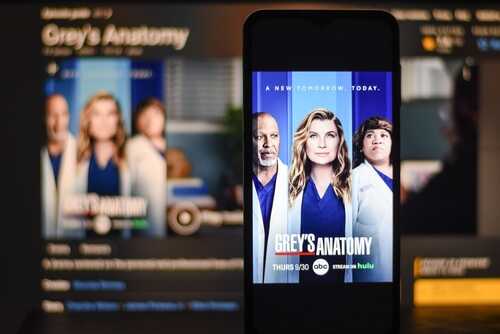 shutterstock_2424141923.jpg Promotional poster for Grey's Anatomy displayed on a smartphone