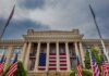 Historic building with large American flag and multiple flags in front