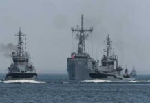 Three naval vessels navigating through the ocean