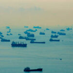 Numerous cargo ships scattered across a hazy ocean
