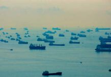 Numerous cargo ships scattered across a hazy ocean
