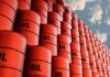 Stacked red oil barrels against a cloudy sky