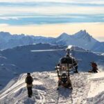 Helicopter on a snowy mountain with people preparing for a rescue operation