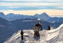 Helicopter on a snowy mountain with people preparing for a rescue operation
