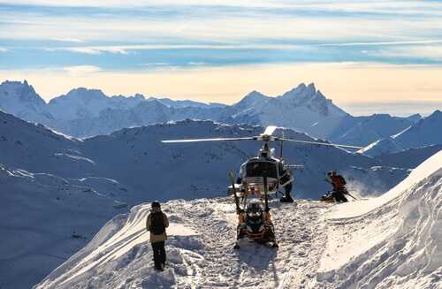 Helicopter on a snowy mountain with people preparing for a rescue operation