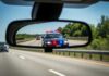 View of a police car with flashing lights in a rearview mirror