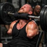 A man lifting a heavy barbell while exercising in a gym