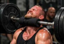 A man lifting a heavy barbell while exercising in a gym