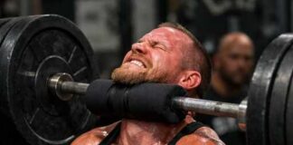 A man lifting a heavy barbell while exercising in a gym