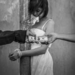 A woman in a white dress appears distressed while two hands exchange money