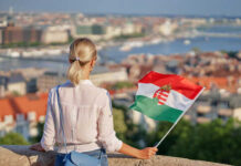 A woman holding a Hungarian flag while overlooking a cityscape
