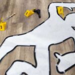 Outline of a body on the floor with evidence markers and tools nearby