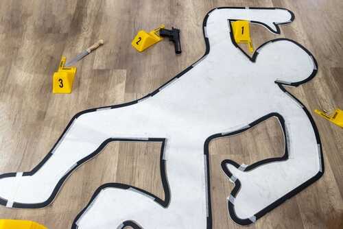 Outline of a body on the floor with evidence markers and tools nearby