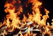 A pile of burning dollar bills engulfed in flames
