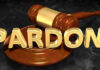 A wooden gavel resting on a circular base with the word 'PARDON' in gold letters