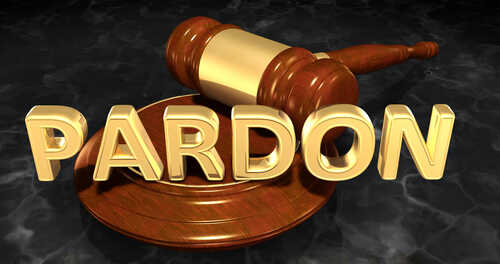 A wooden gavel resting on a circular base with the word 'PARDON' in gold letters