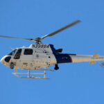 A U.S. Customs and Border Protection helicopter flying against a clear blue sky