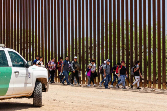 Border Patrol vehicle near group of people walking