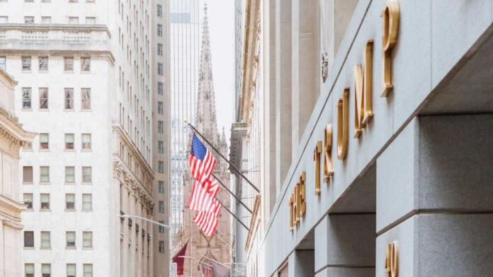 American flag on building corner with spire in background.