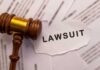 Judge’s Risky Chance Ends in Gunfire A wooden gavel next to a torn paper with the word 'LAWSUIT'