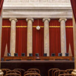 Interior view of a courtroom with red curtains and marble columns