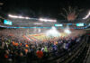 A large crowd celebrating at a football game with fireworks in the background