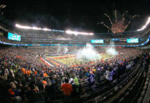 A large crowd celebrating at a football game with fireworks in the background