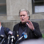 Man speaking at press conference with microphones.