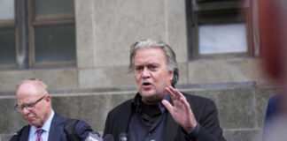Man speaking at press conference with microphones.