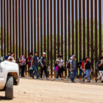 Border Patrol vehicle near group of people walking