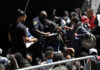 Crowd of people near police officer holding papers