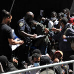 Crowd of people near police officer holding papers