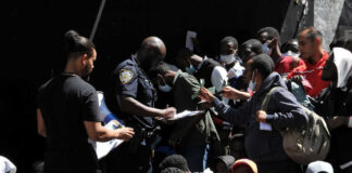 Crowd of people near police officer holding papers