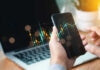 Market Manipulation Bombshell Targets Santos Hands holding phone with financial graph overlay