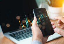 Hands holding phone with financial graph overlay